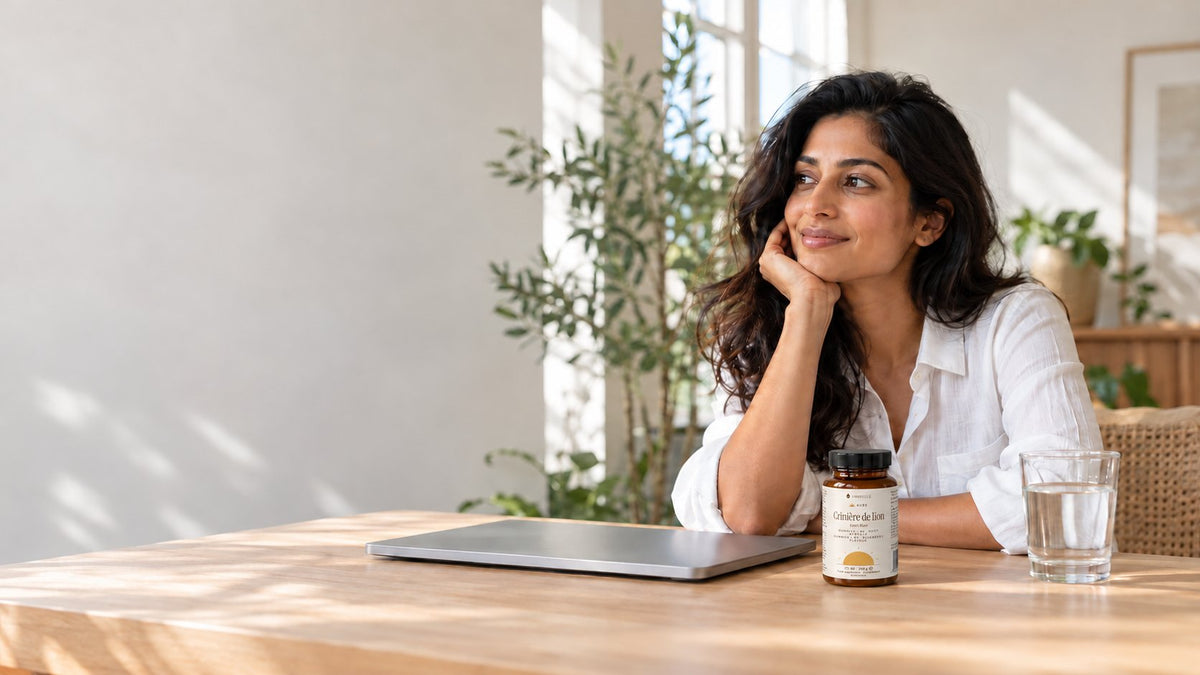 Pot de gummies crinière de lion + B6 AMBRELLE : une femme à son bureau, ordinateur fermé, à côté d'un verre d'eau